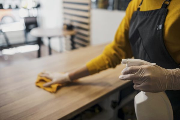 side-view-female-barista-cleaning-table-while-wearing-latex-gloves